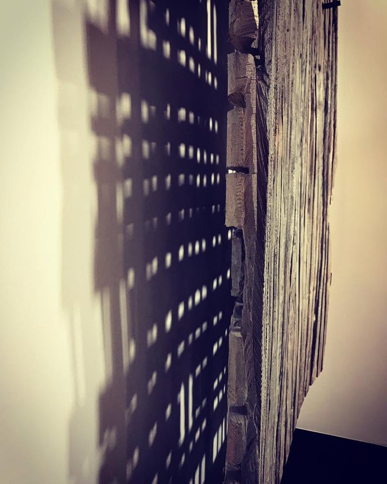 Zij aanzicht van een houtsculptuur met schaduw op de muur
